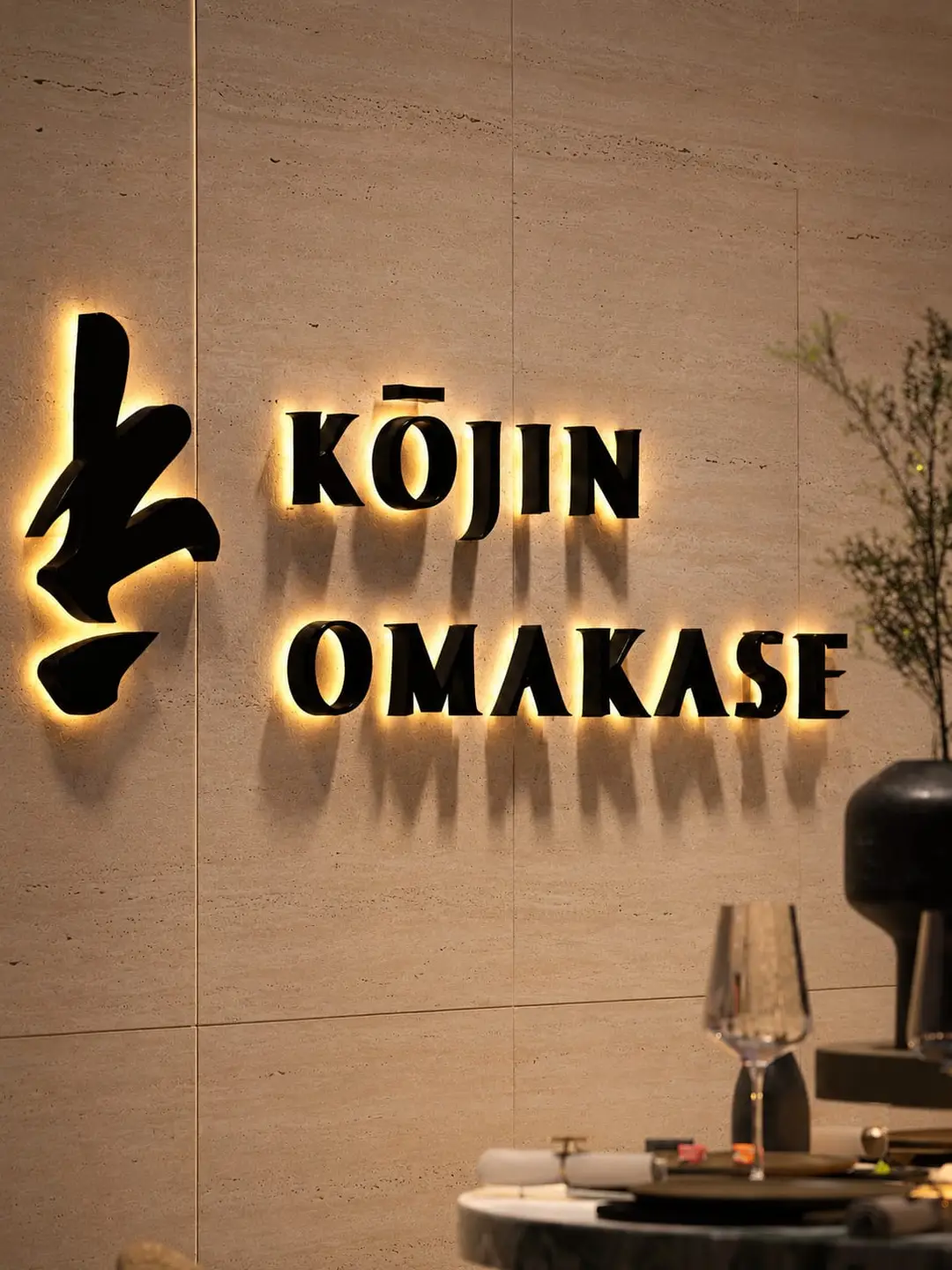 Acceso al restaurante Kōjin Omakase con letrero retroiluminado